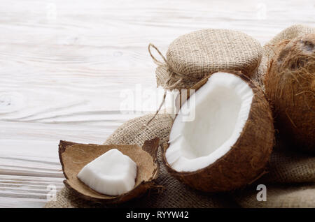 Coconut Shell mit Fleisch auf Hanf Sack auf weißen Küche aus Holz Tisch Stockfoto