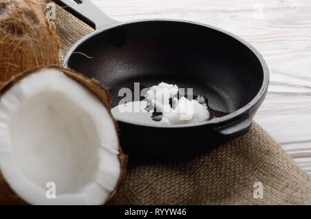 Kokosnuss, Shell mit Fleisch, Gusseisen Skillet auf Hanf Sack auf weißen Küche aus Holz Tisch Stockfoto