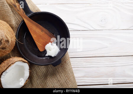 Kokosnuss, Shell mit Fleisch, Gusseisen Skillet und Spachtel auf Hanf Sack auf weißen Küche aus Holz Tisch Stockfoto