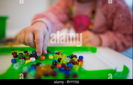 Stuttgart, Deutschland. 15 Mär, 2019. Ein Kind nimmt eine Perle in einer Kindertagesstätte. Credit: Sebastian Gollnow/dpa/Alamy leben Nachrichten Stockfoto