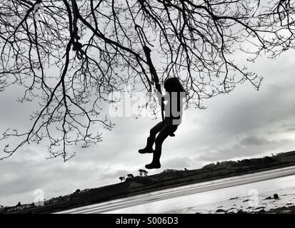 Mädchen Kind Schaukeln am Seil an einem Baum. Abenteuer am Ufer Flusses. Stockfoto