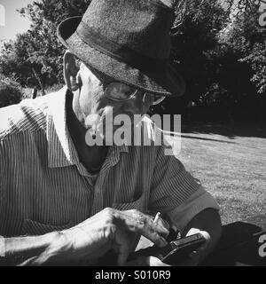 Älterer Mann spielt auf Smartphone Stockfoto