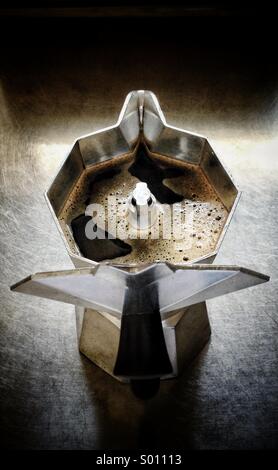 Die Ansicht von oben nach unten zeigt die ikonische achteckige Form einer Bialetti Moka-Kanne, deren Deckel geöffnet ist, um frisch gebrühten, dunklen Kaffee im Inneren freizulegen. Stockfoto