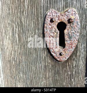 Schlüsselloch Türschild auf einem Vintage Holztür in Herzform Stockfoto