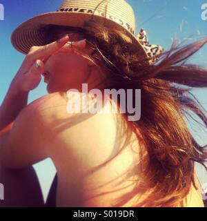 Junge schöne Frauen mit langen, dunklen Haaren und Hut am Strand Stockfoto
