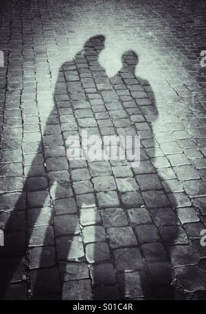 Schatten von Mann und Frau auf Kopfsteinpflaster Stockfoto