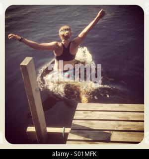 Eine Frau an einem Pier in einen See springen Stockfoto