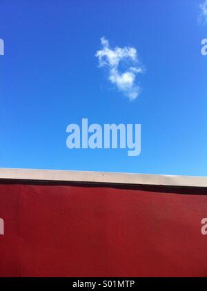 Rote Wand und blauer Himmel mit der cloud Stockfoto