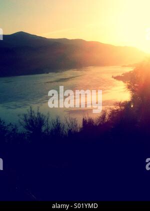 Sonnenuntergang im Tal mit dem Fluss zwischen den Hügeln Stockfoto