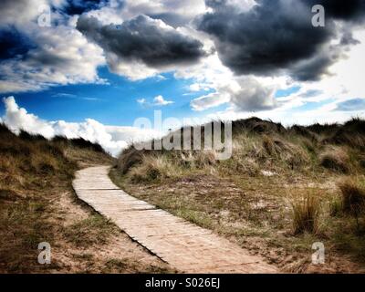 Ein Holzsteg unter den Sanddünen am Strand Stockfoto