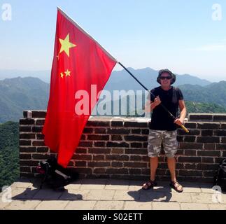 Person winken die chinesische Flagge auf der chinesischen Mauer. Stockfoto