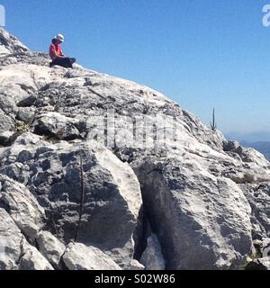 Ein Tourist sitzt oben auf Simancon Berggipfel in den Parque Natural Naturpark Sierra de Grazalema, Grazalema, Cadiz Provinz, Andalusien, Spanien Stockfoto