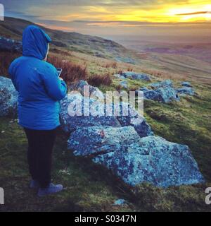 Frau Fotografieren eines Sonnenuntergangs auf ihrem iPhone Stockfoto