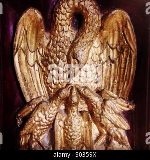 Eine goldene Skulptur aus Holz, die Darstellung eines Adlers, die Fütterung der Jungvögel in ihr Nest schmückt eine Kirche in El Ronquillo, Provinz Sevilla, Andalusien, Spanien Stockfoto
