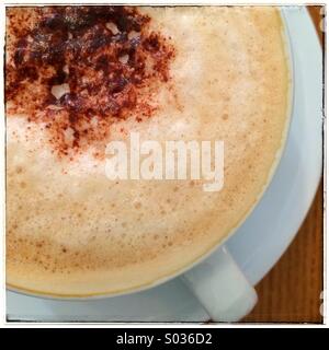 Einer schaumigen Tasse Cappuccino mit einer Schokoladenglasur in einem Milchkaffee Tasse und Untertasse. Stockfoto