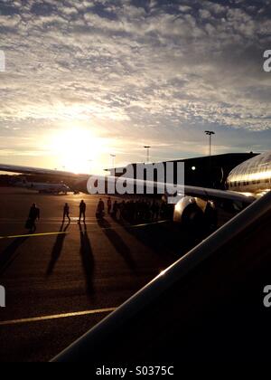 Um in einem Ryan Air Flugzeug in Billund, auf der Halbinsel Jütland, Dänemark, steigen mit dem Sonnenuntergang im Hintergrund und die Silhouetten der Passagiere, für einen Flug von Billund nach Faro, Portugal Stockfoto