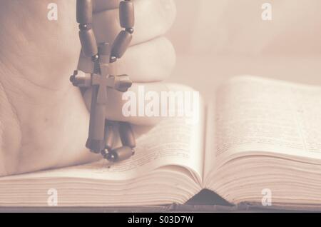 Christlichen Holzkreuz in der Hand auf die Bibel. Stockfoto