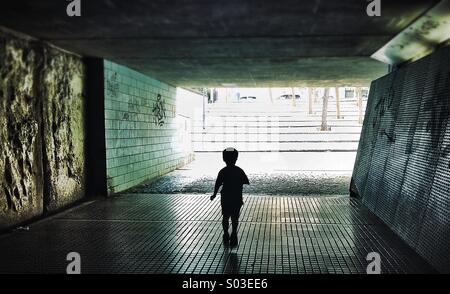 Silhouette einer Person zu Fuß durch eine dunkle Unterführung symbolisiert Licht am Ende des Tunnels Stockfoto