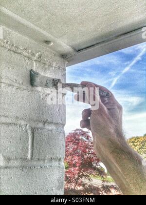 Menschenhand Malerei eine weiße Mauer gegen blauen Himmel mit Flugzeug-trail Stockfoto