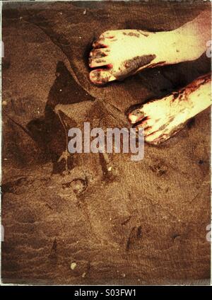 Schlammige Füße des Kindes im nassen sand Stockfoto