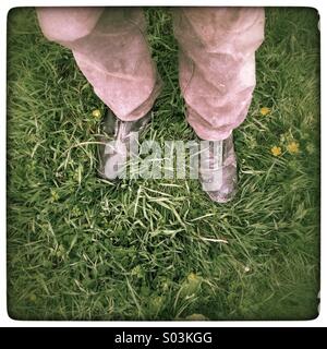 Mannes Füßen Gras in Stiefeln Stockfoto