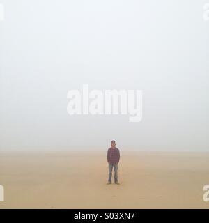 Porträt einer einsamen Person stehen am Strand in schwere See-Nebel. Stockfoto