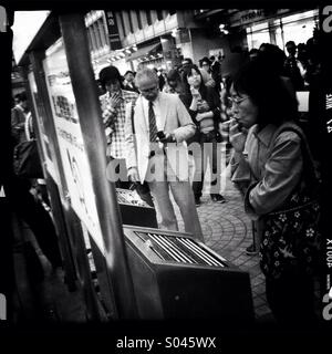 Drängen sich Raucher in einen Raucherbereich in Shinjuku, Tokyo. In den meisten Stationen in Tokio ist das Rauchen während des Gehens oder auf der Straße verboten. Stockfoto