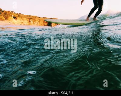 Surfer auf einem Longboard bei Sonnenuntergang im Sommer Stockfoto