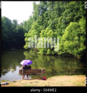 Mutter und Tochter sitzen auf Bank Weiher Stockfoto