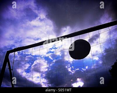 Fußball ins Tor gegen dramatischer Himmel fliegen Stockfoto