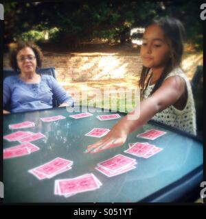 Kleine Mädchen-Spielkarten mit ihrer Großmutter Stockfoto