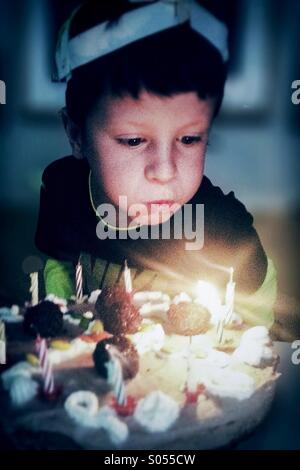 Junge feiert seinen Geburtstag und Ausblasen der Kerzen auf dem Kuchen Stockfoto