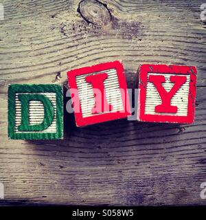 Es ist ein Foto von drei Holz Würfel Spielzeug mit Buchstaben, die das Akronym DIY für Do bilden sie sich selbst Stockfoto