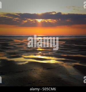 Ein Sonnenuntergang am Strand mit Wasserbecken spiegelt den Sonnenuntergang. Watergate Bay, Newquay Cornwall England UK. Stockfoto