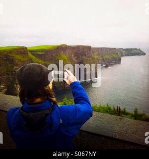 Eine Frau, die ein Foto von den Klippen von Moher. County Clare, Irland Europa. Stockfoto