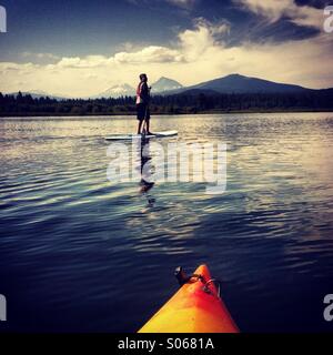 Junge auf Paddleboard auf See in Bergen. Stockfoto