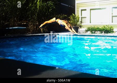 Frau in Hinterhof Schwimmbad tauchen. Stockfoto