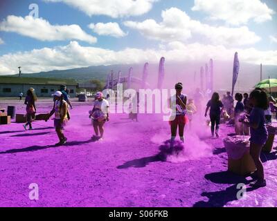 Teilnehmer laufen beim Color Run in Kailua-Kona, Big Island Hawaii, durch purpurnes Pulver – lustiges Rennen, Festival, Fitness- und Lifestyle-Konzept Stockfoto