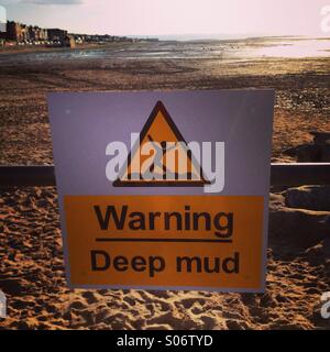 Ein Schild Warnung vor tiefem Schlamm an einem Strand in Hoylake, England Stockfoto