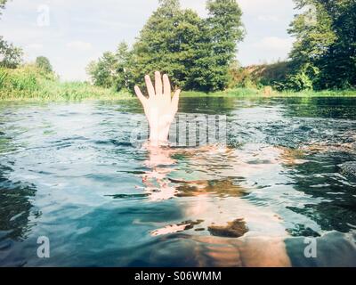 Junge in einem reinen Fluss hält seine Hand über dem Wasser untergetaucht Stockfoto