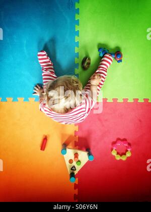 Baby spielt auf farbenfrohe Spielmatte Stockfoto