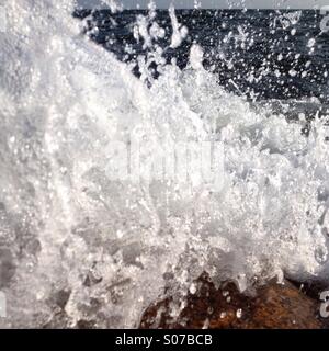 Eine Welle an Felsen gefangen im letzten Moment bevor es das Objektiv trifft brechen Stockfoto