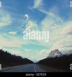 Autobahn durch Alberta Rockies Schlossberg an einem sonnigen Tag mit interessanten Wolken nähert. Stockfoto