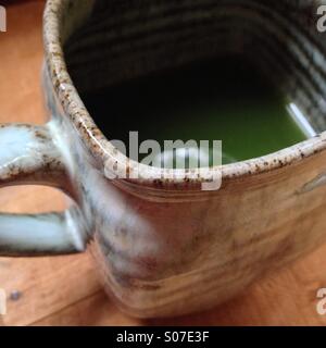 Handgemachte Keramik Becher auf Holztisch mit Matcha-Grüntee. Stockfoto