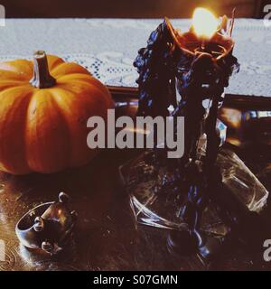 Halloween-Stillleben mit kleiner Kürbis, schwarzen tropfende Kerzen, Totenkopfring am Silbertablett. Stockfoto