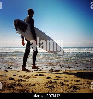 Eine Surfer geht bis zum Strand. Ventura Kalifornien USA.