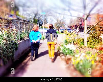 Zwei Frauen gehen auf Bürgersteig im Frühjahr Stockfoto