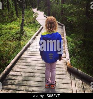 Ein junges Mädchen auf der Suche auf einen Weg durch einen dichten Wald in Nordfinnland in einem riesigen Nationalpark. Ein symbolischer gewundenen Weg vor uns... Stockfoto