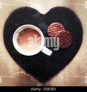 Eine Tasse Tee Witz zwei Schokoladenkekse sitzt auf einer Schiefertafel Herz. Stockfoto
