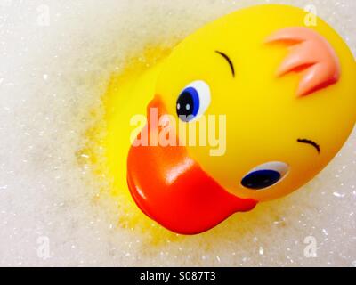 Bild einer gelben Kunststoff Ente schwimmend auf schaumigen Bläschen Stockfoto